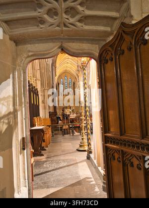 Verzierter Torbogen zur Kathedralen-Nave - Blick durch einen kunstvollen steinernen Torbogen in das große Langhaus einer historischen europäischen Kathedrale mit Buntglasfenstern Stockfoto