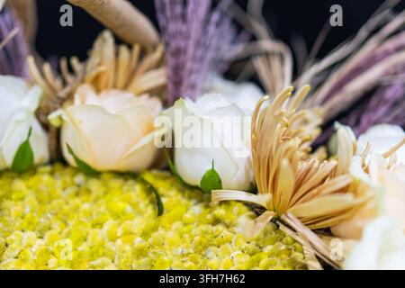 Blumenarrangement mit weißen Rosen, gelben Chrysanthemen, getrocknetem Laub, harmonischen Farben, weicher Beleuchtung, geringer Schärfentiefe, eleganter Komposition Stockfoto