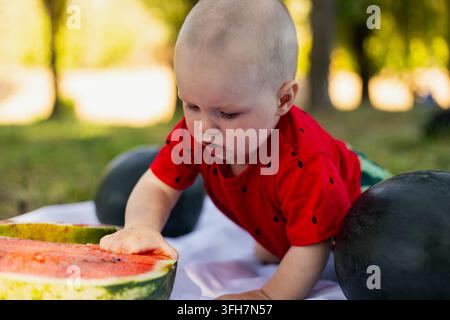Familienpicknick in der Natur mit Mutter und Baby, die draußen an einem sonnigen Sommertag eine Wassermelone genießen. Stockfoto