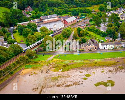Luftbild eines Personenzugs, der Ravenglass neben Gezeitenflächen in Cumbria passiert; ideal für Eisenbahnreisen, Transport, Tourismus und Destinationsmarketing Stockfoto