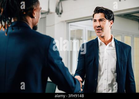 Geschäftsleute und Geschäftsfrauen schütteln sich in einem Büro die Hände und feiern ihre erfolgreiche Partnerschaft und Leistung. Kollegen aus verschiedenen Berufen Stockfoto