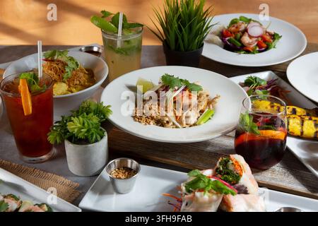 Eine Ansicht mehrerer thailändischer Gerichte auf einem Esstisch, darunter Pad Thai, Panang-Curry, Hähnchensatay, grünes Curry und Garnelen-Miang Kham. Stockfoto