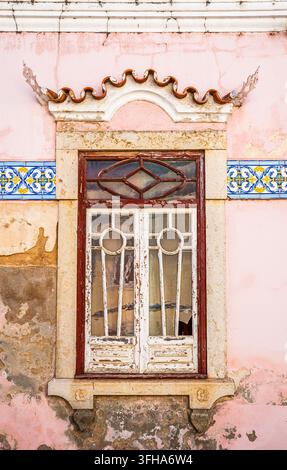 Malerisches traditionelles Fenster in Faro mit geschwungenen Dachziegeln und dekorativen portugiesischen Azulejo-Fliesen an der Fassade, Faro, Algarve, Portugal Stockfoto