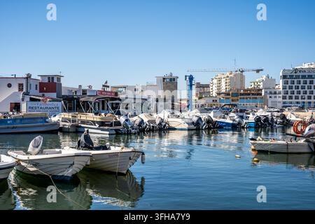 Kleine Boote, die in der Faro Marina festgemacht sind, mit dem Ufer und dem historischen Stadtzentrum im Hintergrund, Faro, Algarve, Portugal Stockfoto