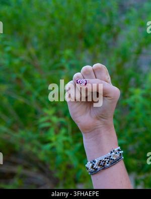 Menschliche Hand zeigt eine erhobene Faust, die Stärke, Macht und Widerstand gegen grünen Hintergrund symbolisiert Stockfoto
