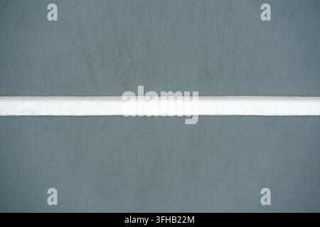 Minimalistische Hintergrundtextur einer glatten grauen Wand mit einem horizontalen weiß gestrichenen Streifen. Stockfoto