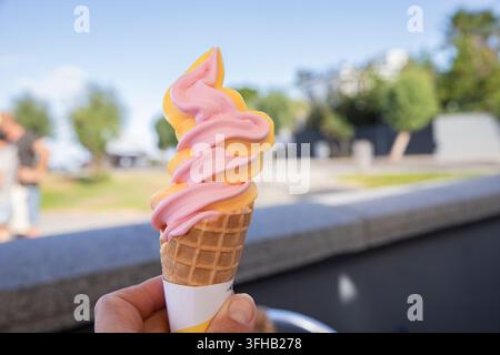 Rosa und orangefarbene Softeis, die im Sommer im Freien gehalten werden Stockfoto