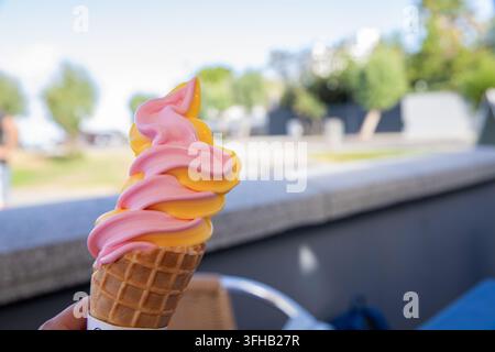 Rosa und orangefarbene Softeis, die im Sommer im Freien gehalten werden Stockfoto
