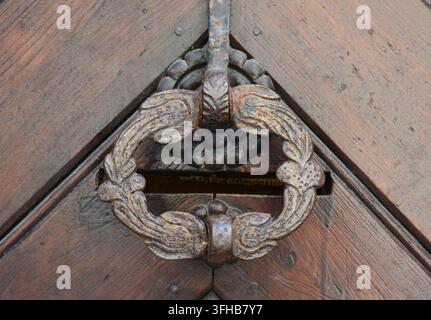 Antike schmiedeeiserne Türklopfer-Details an einer historischen Holztür Stockfoto