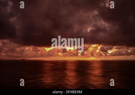 Dramatische Sturmwolken, die vom Sonnenuntergang über dem offenen Meer beleuchtet werden Stockfoto