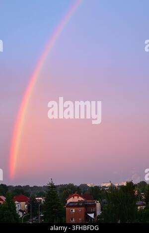 Vertikale Aufnahme eines hellen Regenbogens über Einfamilienhäusern in Lubin während des Sonnenuntergangs. Stockfoto