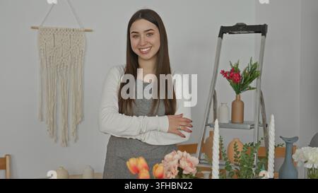 Blumenfrau, die an Blumen steht, Arme im Atelier zwischen Vasen und Leiter gekreuzt; ruhiges Vertrauen. Stockfoto