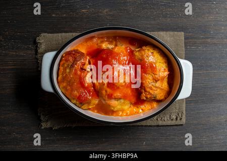 Gebackene Kohlrouladen mit Tomatensoße, Oberansicht, Nahaufnahme. Traditionelle gefüllte Kohlrouladen oder Hackbraten, gebacken in herzhafter roter Tomaten- und Sauerrahmsoße Stockfoto
