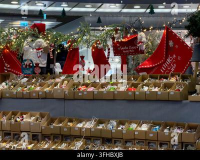 Posen, Polen – 13. Dezember 2025: Reihen von saisonalen Kugeln, die in Kartons zum Verkauf auf einem festlichen Marktstand angeordnet sind, dekoriert mit Lichtern und Stockfoto