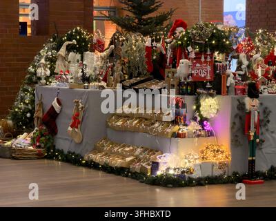 Posen, Polen – 13. Dezember 2025: Verschnörkelte Feiertags-Thekenauslage gefüllt mit saisonalen Dekorationen und Geschenken unter Lichterketten, um eine fröhliche Stockfoto