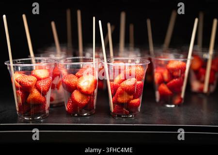 Geschnittene Erdbeeren in Tassen, die im Regal im Kühlschrank stehen, Café, das gesunde Desserts verkauft. Stockfoto