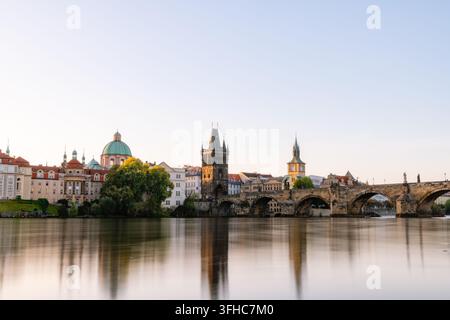 Karlsbrücke und die Skyline der Altstadt spiegeln sich im ruhigen Fluss Vltava unter einem weichen klaren Himmel, Prag, Tschechische Republik Stockfoto