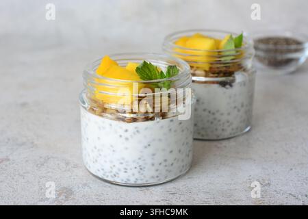 Mango-Chia-Samen-Pudding in kleinen Gläsern, dekoriert mit Mango und Walnüssen Stockfoto
