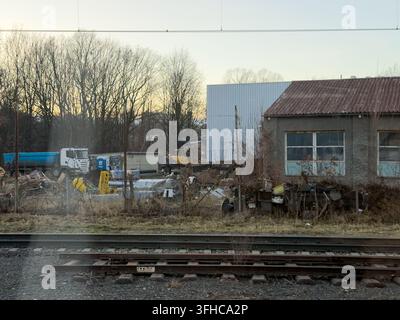 Wroclaw, Polen – 15. Dezember 2025: Industrieanlagen und ein schwerer Muldenkipper ruhen an einer Baustelle entlang der Bahnstrecken, während eine verwitterte Fabrik i Stockfoto