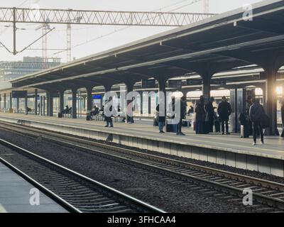 Posen, Polen – 15. Dezember 2025: Pendler mit Gepäck stehen auf einem Bahnsteig im Freien und warten auf die Abfahrt, repräsentativ für Verkehrsinfrastruktur Stockfoto