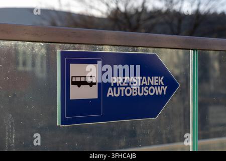 Nahaufnahme eines blauen pfeilförmigen Schildes mit der Aufschrift PRZYSTANEK AUTOBUSOWY, das eine Bushaltestelle anzeigt, unerlässlich für effiziente öffentliche Verkehrsmittel und die Stadtorientierung Stockfoto