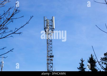 Hocher Mobilfunktelekommunikationsmast mit einem komplexen Array moderner Antennen vor einem lebendigen klaren blauen Himmel, der den wesentlichen mobilen Empfang ermöglicht Stockfoto