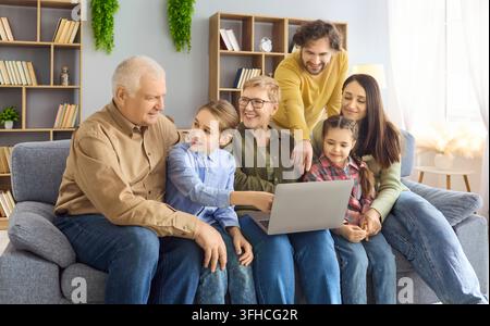 Mehrgenerationenfamilie mit Großeltern, Eltern und Kindern, die einen Laptop nutzen Stockfoto