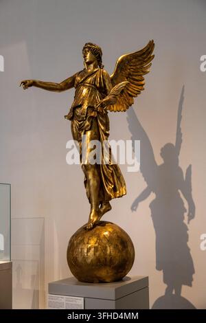 Berlin, Deutschland – 8. Nov. 25: Vergoldete geflügelte Siegesstatue auf einem Globus, ausgestellt in der Skulpturengalerie des Alten Museums in Berlin. Stockfoto