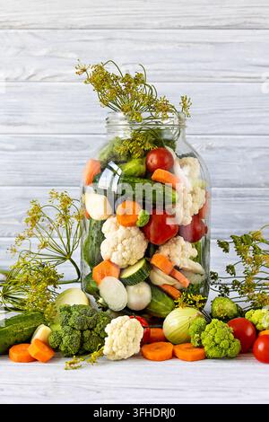 Glas mit bunten eingelegten Gemüsen auf weißem Hintergrund Stockfoto