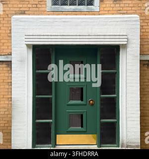 Tür aus der Mitte des Jahrhunderts mit vertikal gestapelten quadratischen Fenstern, flankiert von breiten gerippten Rahmen. Stockfoto