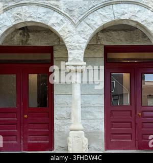 Zwillingsburgunder-Eingänge unter angrenzenden runden Steinbögen, die von einer schlanken Mittelsäule gestützt werden. Stockfoto