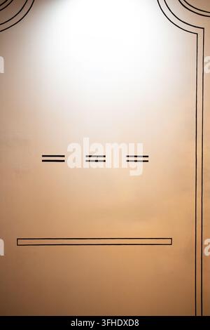 Eine vertikale Innenaufnahme einer glatten, warmtönigen Wand mit minimalistischer schwarzer Linienkunst. Ein gebogener Rahmen ziert die obere Kante, begleitet von Stockfoto