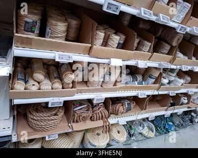 Denia, Spanien – 10. Oktober 2025. Verschiedene Spulen aus natürlichem Jutegarn und dicke Sisalseile sind auf Regalen in einem spanischen Baumarkt organisiert Stockfoto
