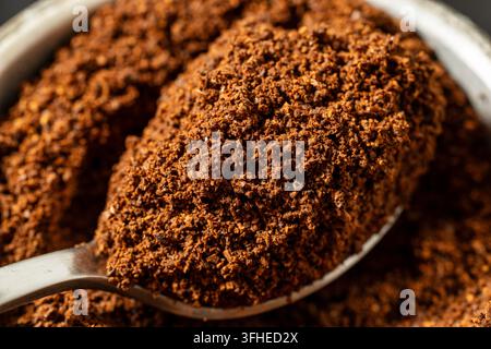 Gemahlener Kaffee auf einem Löffel, Nahaufnahme von frisch gemahlenem geröstetem Kaffee mit reichhaltiger brauner Textur, aromatischer Bestandteil für die Zubereitung von Heißgetränken Stockfoto