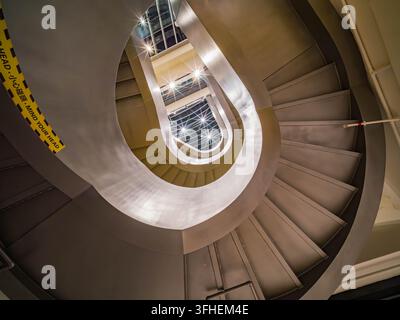 Macau, China, 17. APR 2024 – Metallstufen winden sich anmutig um ein zentrales Voids und führen das Auge nach oben zu hellem natürlichem Licht, das durch ein Stockfoto