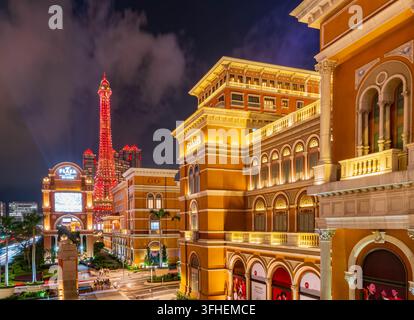 Macau, China, 16. APR 2024 – Ein leuchtend roter Turm erhebt sich im Hintergrund, während großartige Gebäude im europäischen Stil mit warmer Beleuchtung eine Stockfoto