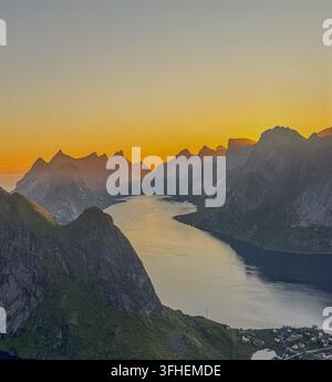 Panoramablick vom Reinebringen über das Fischerdorf Reine, dramatische Berge und Fjorde in den Lofoten während der Mitternachtssonne Stockfoto