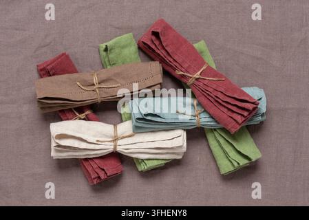 Farbige Leinen servietten auf braunem Leinenstoff. Oberansicht, Flat Lay. Öko-Stoffkonzept. Stockfoto