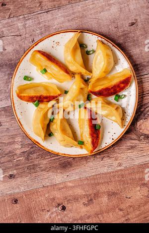 Knödel auf einem Teller mit grünen Zwiebeln in einer einfachen Kücheneinrichtung während des Mittagessens Stockfoto