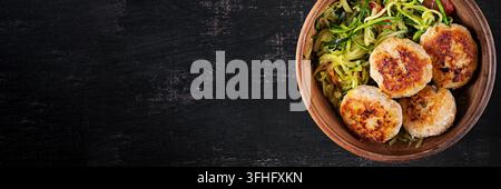 Zucchini-Spaghetti-Pasta mit Hühner-Fleischbällchen in einer Schüssel. Oberansicht. Banner Stockfoto