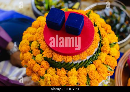 Zwei blaue Ringkästchen, die auf einem lebendigen Ringelblumenarrangement für eine Hochzeit platziert sind Stockfoto