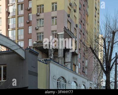 Zerstörte Wohnhochhausstruktur mit freigelegtem Beton und zerschmetterten Außenwänden, die die harte Realität von Kriegsschäden und Post- Stockfoto