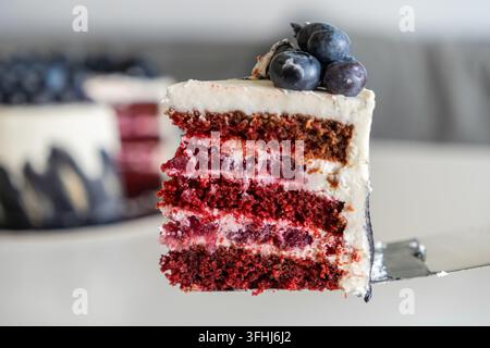 Reicher roter Samt-Schaumkuchen, geschichtet mit cremiger Glasur und saftigen Kirschen, der auf einem Kuchenheber liegt und eine elegante Visualisierung für Bäckereimenüs, Essensb Stockfoto