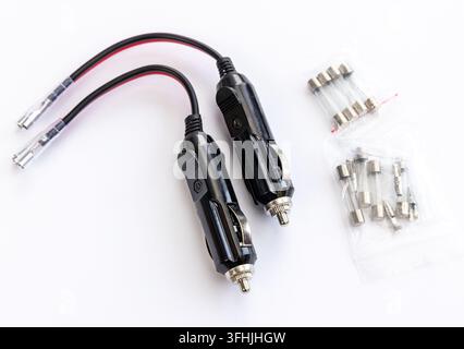 Zwei Auto-Stromstecker und Ersatzsicherungen liegen auf einer weißen Oberfläche Stockfoto