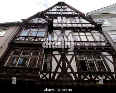 Niedrigwinkelaufnahme eines verzierten mittelalterlichen Fachwerksgebäudes mit dunklen Holzbalken und weißem Putz in Marburg, Deutschland. Stockfoto