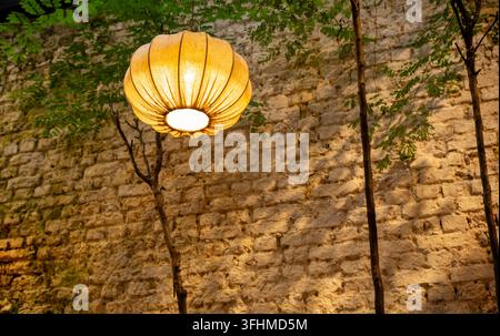 Leuchtende Stoff-Kürbislaterne vor einer rustikalen Ziegelhofmauer Stockfoto