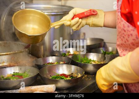 Heißes Brühe in Nudelschüsseln in einer koreanischen Restaurantküche gießen Stockfoto