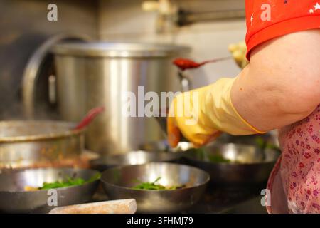 Heißes Brühe in Nudelschüsseln in einer koreanischen Restaurantküche gießen Stockfoto