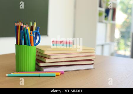Bücher und Schreibwaren auf einem Holzschreibtisch im Klassenzimmer, Nahaufnahme. Platz für Text Stockfoto