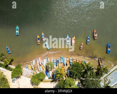 Luftbild von bunten Fischerbooten, die entlang des sandigen Strandes von Las Galeras mit üppigen Palmen und klarem Wasser in Samana, Provinz Samana, Dom Stockfoto